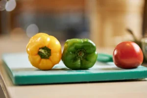 Picture of bell peppers and tomato in a chopping board