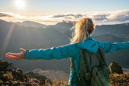 Women spreading her arms in a top of the mountain